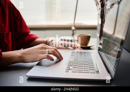 Primo piano di donna seduta al tavolo e digitando sul portatile in ufficio, lei che lavora con rapporto finanziario Foto Stock