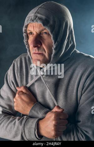 Un uomo bianco di mezza età indossa una felpa con cappuccio per proteggersi dal freddo e dalla nebbia Foto Stock