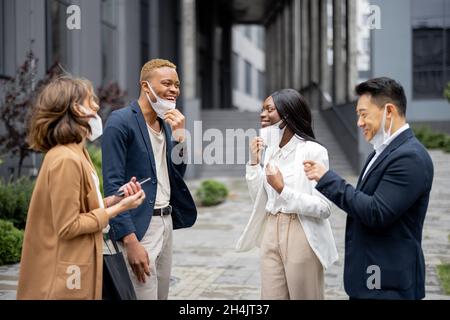 Business team togliere maschere mediche e parlare Foto Stock