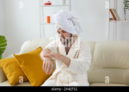 L'uomo bearded sfrega mano crema sulle sue mani. Spa, cura del corpo e della pelle per l'uomo concetto Foto Stock