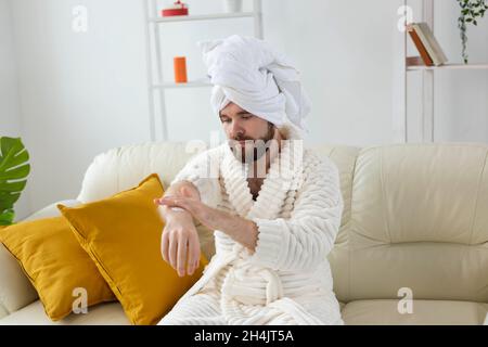 L'uomo bearded sfrega mano crema sulle sue mani. Spa, cura del corpo e della pelle per l'uomo concetto Foto Stock