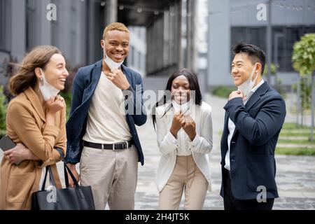 Business team togliere maschere mediche e parlare Foto Stock