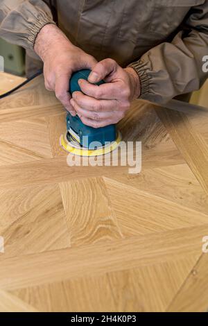 primo piano della mano del falegname usando un macinacaffè su una superficie di legno Foto Stock