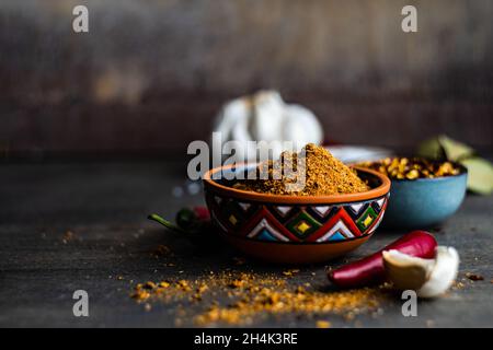 Ciotola di spezie adjika con peperoncino secco, peperoncino, sale, aglio e foglie di alloro su un tavolo Foto Stock