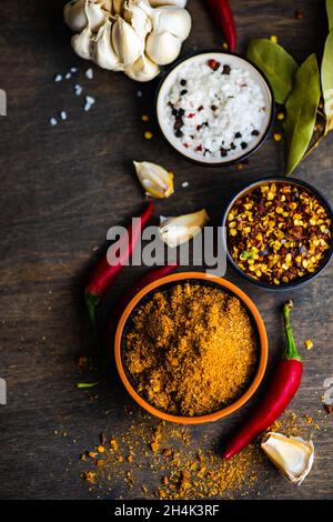 Ciotola di spezie adjika con peperoncino secco, peperoncino, sale, aglio e foglie di alloro su un tavolo Foto Stock