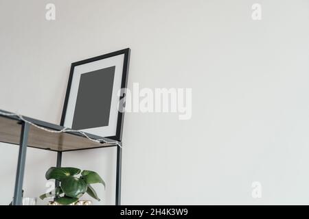 La cornice fotografica in legno bianco si trova all'interno su uno sfondo bianco. Cornice poster mockup. Foto Stock