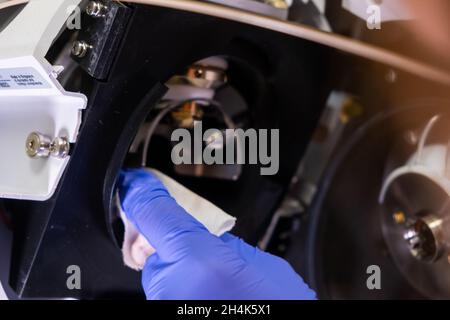 Pulizia della fonte di ioni dello spettrometro di massa da parte di un operatore di laboratorio con guanti di gomma. LC MS, cromatografia liquida e routine quotidiana Foto Stock