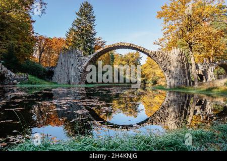 Ponte unico Rakotzbrucke, chiamato anche Devils Bridge, Sassonia, Germania. Costruito per creare cerchio quando si riflette in Waters.colorful caduta terra Foto Stock