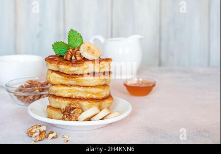 Pancake fatti in casa con noci, miele e banana su uno sfondo chiaro. Vista laterale. Orizzontale. Foto Stock
