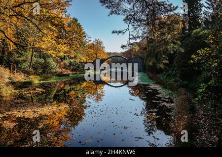 Ponte unico Rakotzbrucke, chiamato anche Devils Bridge, Sassonia, Germania. Costruito per creare cerchio quando si riflette in Waters.colorful caduta terra Foto Stock