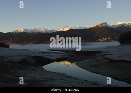Sunup in inverno nevoso lago Plastiras con un bel villaggio in background.Plastiras Lago, Karditsa, Grecia centrale, Europa Foto Stock