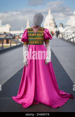 Una donna afghana completamente coperta in un abito tradizionale rosa sul Millennium Bridge di Londra. Foto Stock