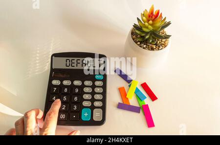 Per impostazione predefinita, il testo viene scritto sul display della calcolatrice. La mano femminile si trova sulla calcolatrice, sfondo bianco con adesivi e fiore di cactus Foto Stock