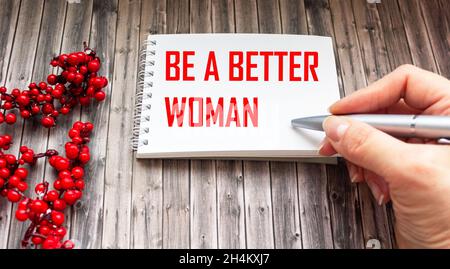 Il testo Be the Best Woman è scritto da una mano di una donna su uno sfondo di legno è un mazzo di cenere di montagna. Foto Stock
