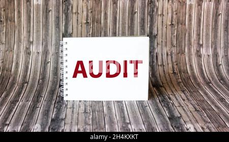 La parola Audit è scritta su un notebook che si trova su un tavolo di legno. Foto Stock