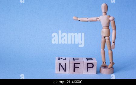 La parola nfp su un cubo con un uomo di legno su sfondo blu Foto Stock