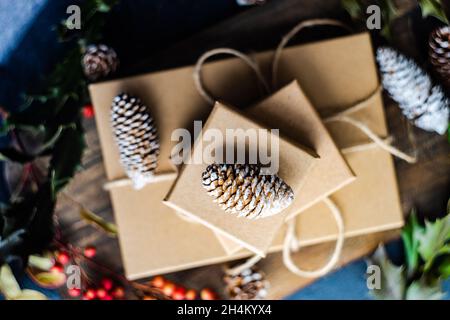 Scatole regalo di Natale decorate con bacche rosse, coni di abete e piante di agrifoglio Foto Stock