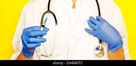 Medico con uno stetoscopio e un vaccino virale su sfondo giallo Foto Stock