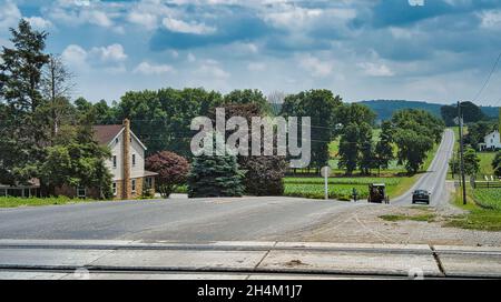 Amish Cavallo e Buggy si avvicina con una coppia e la famiglia in un giorno di sole Foto Stock