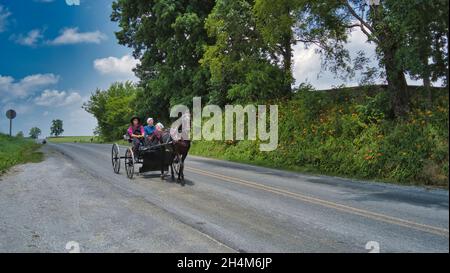 Ronks, Pennsylvania, 2021 giugno - Amish Open Horse and Buggy si avvicina con una coppia e una figlia in esso in una giornata di sole Foto Stock