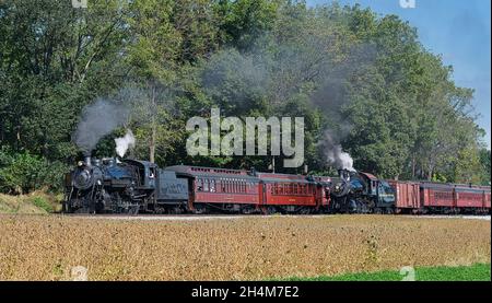 Ronks, Pennsylvania, ottobre 2019 - Vista di due antichi restaurati treno a vapore passeggeri soffiando fumo e vapore in un Sunny Summer Day Foto Stock