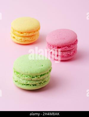 Torta macaron o macaroon biscotti di mandorle colorate, colori pastello su uno sfondo rosa Foto Stock