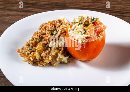 Insalata di tabbouleh con pomodoro ripieno. Cibo vegetariano. Piatto tradizionale medio-orientale o arabo. Vista dall'alto Foto Stock