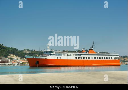 Grande traghetto rosso per il trasporto di merci e persone nel Mar Mediterraneo vicino al lungomare dell'isola greca, Grecia. Foto Stock