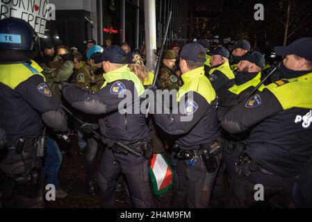 L'Aia, Paesi Bassi. 2 novembre 2021. La polizia si scontra con i manifestanti durante la manifestazione. La polizia ha arrestato tredici persone durante una manifestazione anti-corona, come nuove misure del Covid 19 sono state annunciate dal primo ministro olandese uscente, Mark Rutte. Qualche centinaio di persone si sono riunite fuori dal “Ministero della Giustizia e della sicurezza” sul Turfmarkt, con il suono assordante di fischi, grida, musica, il banging di pentole e tamburi da cucina, e le occasionali fuochi d’incendio e razzi rossi. Credit: SOPA Images Limited/Alamy Live News Foto Stock