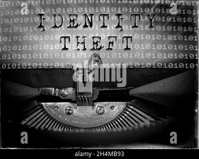 Furto di identità visualizzato su una macchina da scrivere vintage con uno sfondo di codice binario Foto Stock