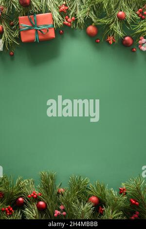 Sfondo verde di Natale con regalo rosso e rami di pino sempreverdi, baubles rosso festivo. Biglietto di auguri di Natale. Felice Anno Nuovo. Spazio per il testo. Visualizza fr Foto Stock
