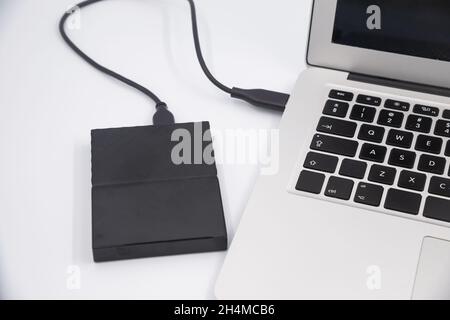 Disco rigido esterno collegato al computer portatile, trasferimento o backup dei dati tra il laptop e il primo piano del disco rigido Foto Stock