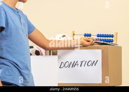 I bambini che raccolgono e mettono giocattoli, vestiti, libri, merci di donazione in scatole di carità donate Foto Stock