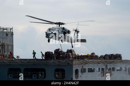 211101-N-LU761-2034 SOUTH CHINA SEA (NOV. 1, 2021) un mH-60 Sea Hawk, assegnato ai “Cavalieri neri” di Helicopter Sea Combat Squadron (HSC) 4, trasporta le forniture a un vettore aereo di classe Nimitz USS Carl Vinson (CVN 70), durante un rifornimento verticale in mare con una nave da carico a secco di classe Henry J. Kaiser USNS Washington Chambers (T-AKE 11), 1 novembre 2021. Carl Vinson Carrier Strike Group è in fase di implementazione nell'area operativa della 7a flotta statunitense per migliorare l'interoperabilità attraverso alleanze e partnership, fungendo da forza di risposta pronta a sostenere un libero e aperto Indo-Pa Foto Stock