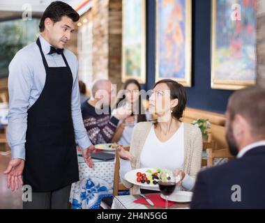 Adulto Giovane esprimere insoddisfazione con cameriere circa il cibo Foto Stock