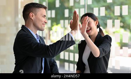 Allegro uomo d'affari e donna d'affari che dà alto cinque, eccitato felice, celebrando, obiettivo di realizzazione. Foto Stock