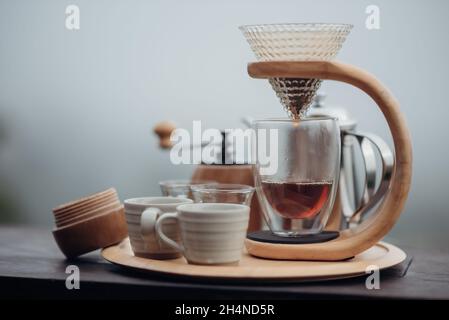 Un set per caffè espresso con bollitore in acciaio, vetro e macchina per caffè espresso in stile minimalista con nebbia e sfondo naturale. Foto Stock