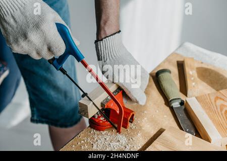 Falegname in guanti di segatura è una tavola di legno con una sega.Сlose-up  Foto stock - Alamy