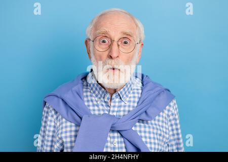 Foto della persona impressionata che staring la macchina fotografica cant crede legato sul maglione del collo isolato su sfondo blu di colore Foto Stock