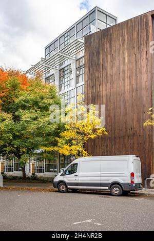 Il mini furgone bianco di piccole dimensioni del carico commerciale ha consegnato le merci al cliente in un alto edificio multi-appartamento con pareti di legno e in piedi sul Foto Stock