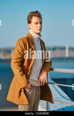 Abbigliamento primavera - autunno. Street fashion. Giovane uomo in pantaloni a scacchi, maglione e cappotto di lana. Foto Stock