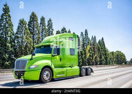 Per uso professionale di livello industriale, verde brillante, potente trattore semi-camion con carro di perforazione grande senza il semirimorchio che corre lungo l'ampia strada statale fino al magazzino Foto Stock