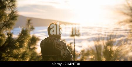Un uomo viaggia ed esplora il concetto di luoghi panoramici all'aperto attività escursionistiche di svago con uomini seduti sulla scogliera e godersi il tramonto e la nuvola Foto Stock