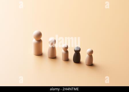 Alto angolo di minimo stile figurine di legno dei genitori con bambini multirazziali posti in linea contro sfondo beige Foto Stock