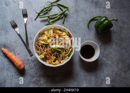 Vista dalla parte superiore delle tagliatelle fritte o della chowmein hakka servita in una ciotola. Foto Stock