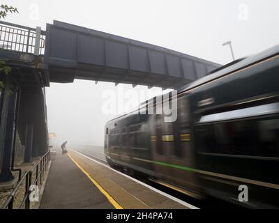 Anche la mondana può essere trasformata dalla bellezza al momento e nel luogo giusti. Qui vediamo singolo, paziente persona in attesa del treno che entra in un altro Foto Stock