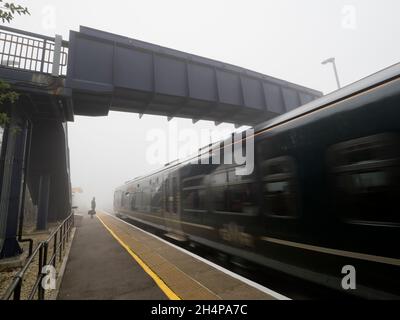 Anche la mondana può essere trasformata dalla bellezza al momento e nel luogo giusti. Qui vediamo singolo, paziente persona in attesa del treno che entra in un altro Foto Stock