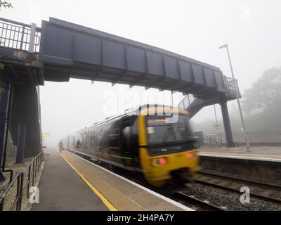 Anche la mondana può essere trasformata dalla bellezza al momento e nel luogo giusti. Qui vediamo singolo, paziente persona in attesa del treno che entra in un altro Foto Stock