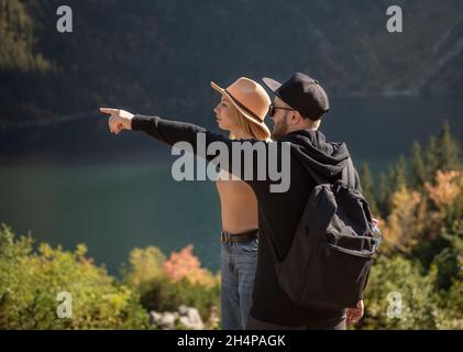 Giovane coppia che viaggia in montagna. Un uomo sta puntando sulla montagna con sfondo naturale Foto Stock