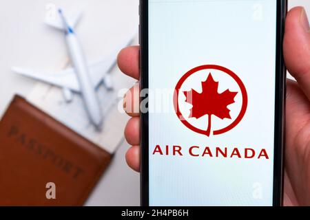 Logo della compagnia aerea Air Canada sullo schermo del cellulare in mano dell'uomo sullo sfondo del passaporto, della carta d'imbarco e dell'aereo, settembre 2021, San Foto Stock